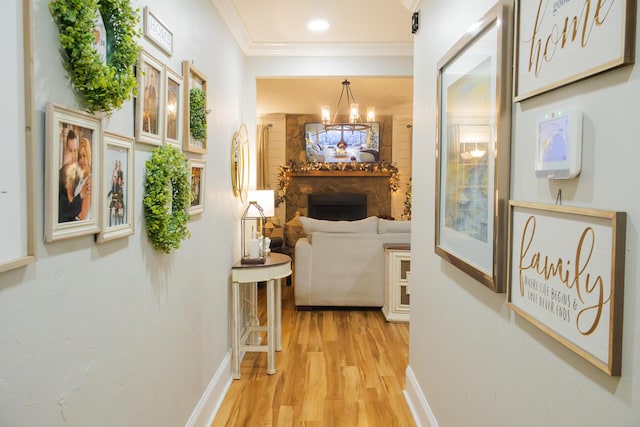 hall featuring an inviting chandelier, crown molding, and light hardwood / wood-style flooring