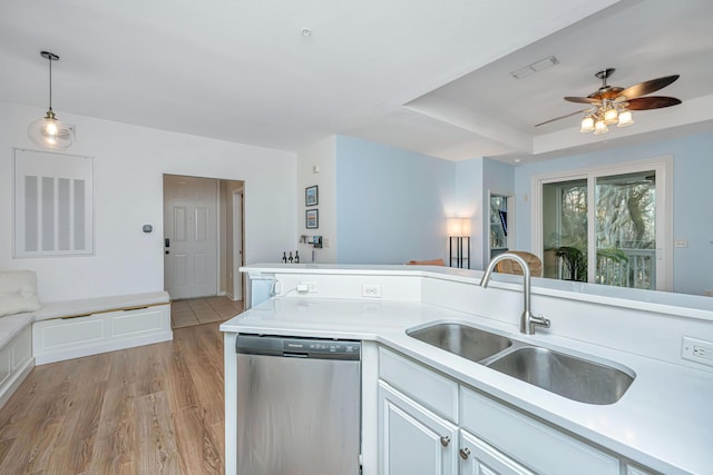 kitchen with sink, white cabinetry, light hardwood / wood-style flooring, stainless steel dishwasher, and pendant lighting