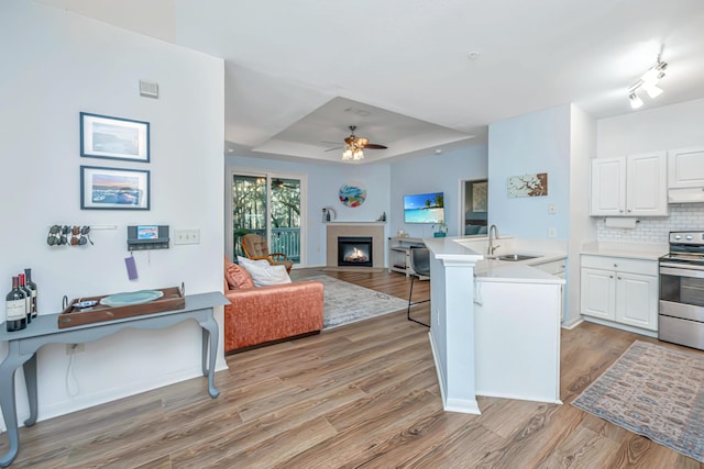 kitchen featuring white cabinetry, stainless steel electric stove, a breakfast bar area, and kitchen peninsula