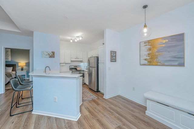 kitchen with white cabinetry, tasteful backsplash, kitchen peninsula, pendant lighting, and stainless steel appliances