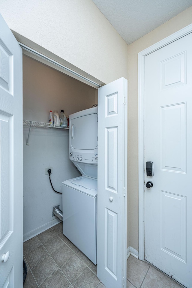 laundry area with stacked washing maching and dryer and tile patterned flooring