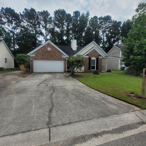 8420 Walsham St, North Charleston, SC 29420 - view of front of property with brick siding, concrete driveway, a front yard, and a chimney