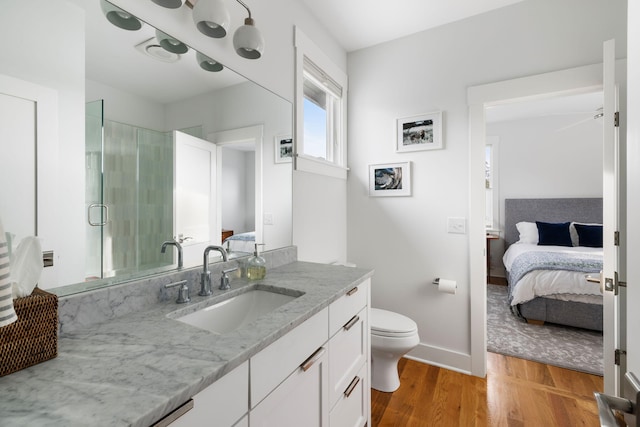 bathroom featuring hardwood / wood-style flooring, vanity, toilet, and a shower with shower door