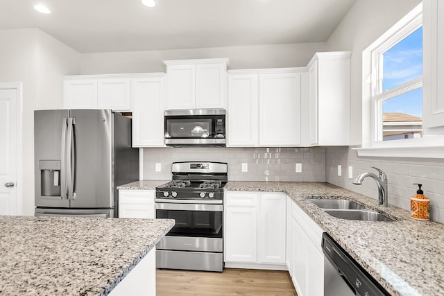 kitchen featuring sink, light stone counters, backsplash, white cabinets, and appliances with stainless steel finishes