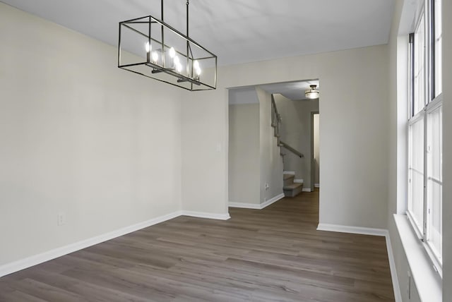 unfurnished dining area featuring a wealth of natural light, dark hardwood / wood-style floors, and a chandelier