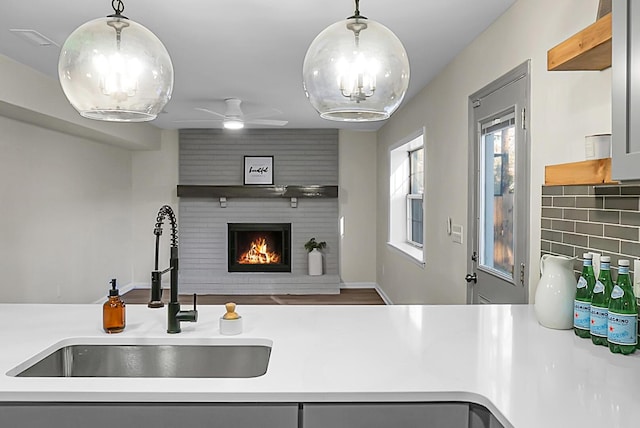 kitchen with ceiling fan, sink, hanging light fixtures, and backsplash