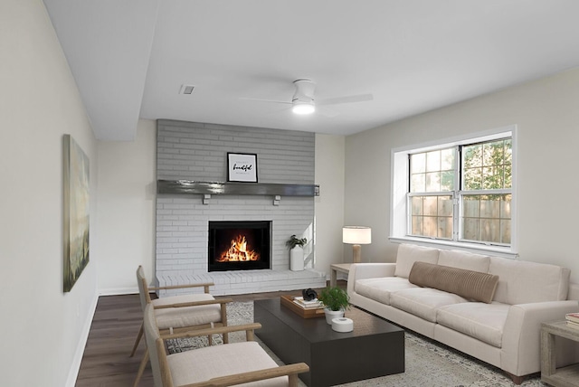 living room with dark wood-type flooring, ceiling fan, and a brick fireplace