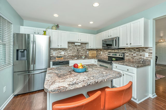 kitchen featuring decorative backsplash, dark wood-type flooring, appliances with stainless steel finishes, and a sink