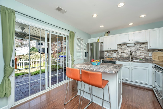 kitchen featuring visible vents, dark wood-type flooring, a sink, a kitchen island, and appliances with stainless steel finishes