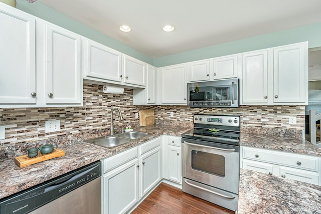 kitchen featuring a sink, decorative backsplash, appliances with stainless steel finishes, and white cabinetry