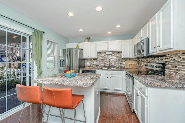 kitchen featuring dark wood-type flooring, a sink, a center island, white cabinetry, and stainless steel appliances