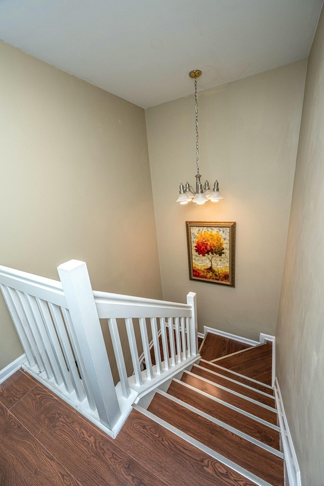 stairway with a chandelier, baseboards, and wood finished floors