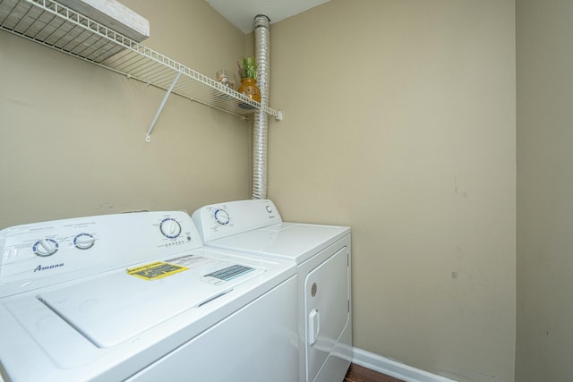 washroom with laundry area, washing machine and dryer, and baseboards