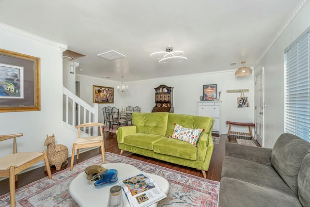 living area with visible vents, wood finished floors, an inviting chandelier, crown molding, and stairs