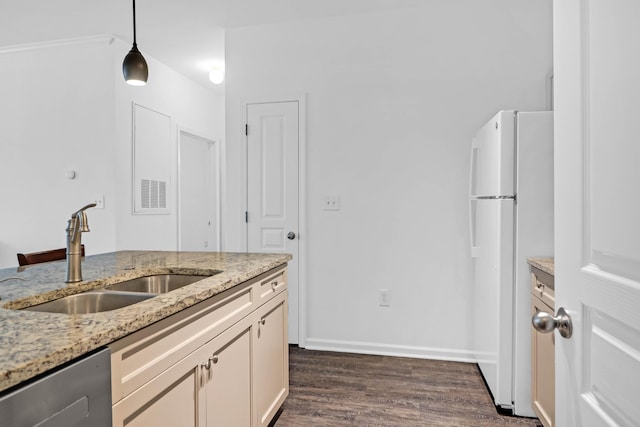 kitchen featuring sink, hanging light fixtures, dishwashing machine, white fridge, and light stone countertops