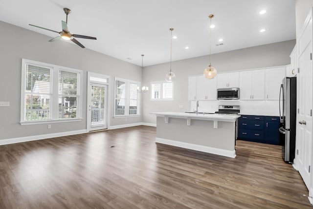 kitchen featuring appliances with stainless steel finishes, a breakfast bar, pendant lighting, white cabinetry, and an island with sink