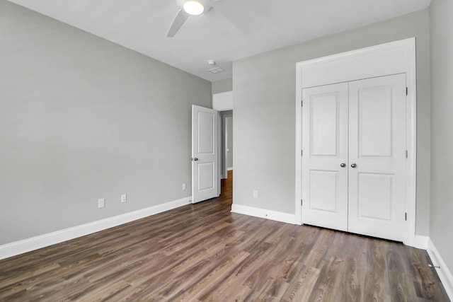 unfurnished bedroom featuring dark wood-type flooring, a closet, and ceiling fan