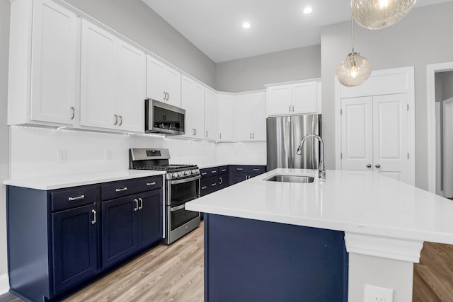 kitchen featuring sink, white cabinetry, decorative light fixtures, a center island with sink, and stainless steel appliances