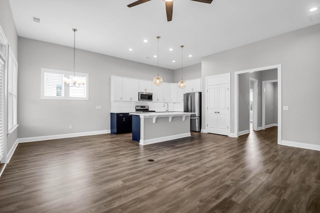 kitchen featuring decorative light fixtures, a center island with sink, a kitchen breakfast bar, and appliances with stainless steel finishes