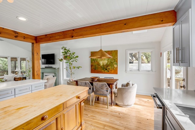 kitchen with vaulted ceiling with beams, light wood-style flooring, open floor plan, hanging light fixtures, and stainless steel dishwasher