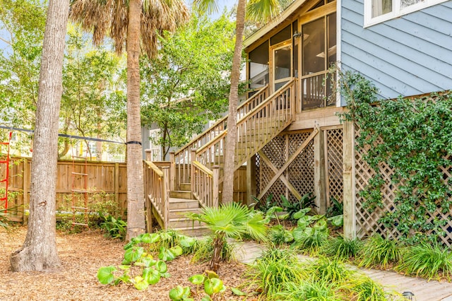 exterior space featuring a sunroom, fence, and stairs