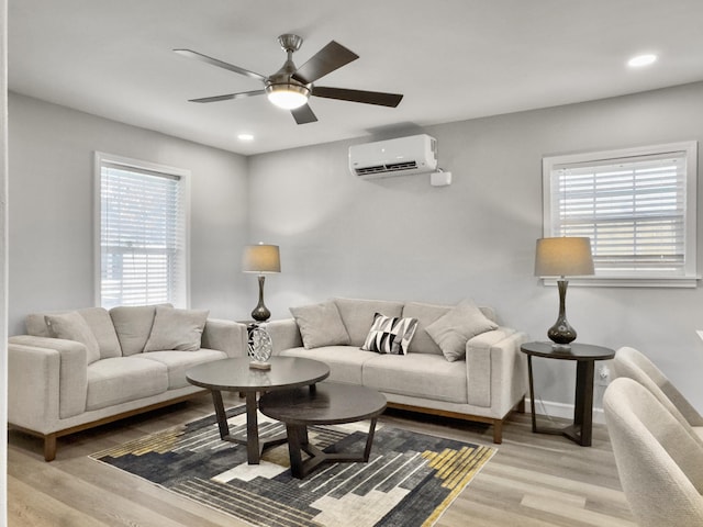 living room featuring ceiling fan, a wall mounted air conditioner, and light hardwood / wood-style floors