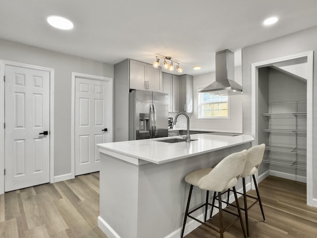 kitchen featuring sink, a breakfast bar area, gray cabinetry, island range hood, and stainless steel fridge with ice dispenser