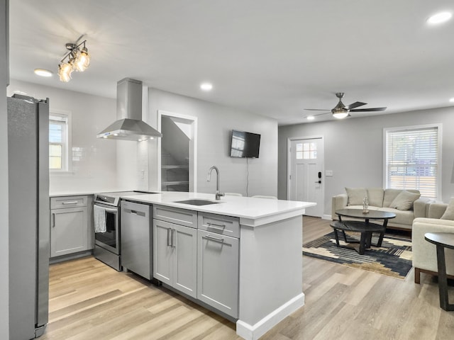 kitchen with sink, gray cabinetry, stainless steel appliances, island exhaust hood, and kitchen peninsula