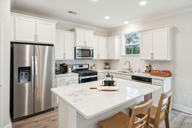 770 Opal Wing St, Moncks Corner, SC 29461 - kitchen with appliances with stainless steel finishes, a sink, light wood-style floors, white cabinetry, and ornamental molding