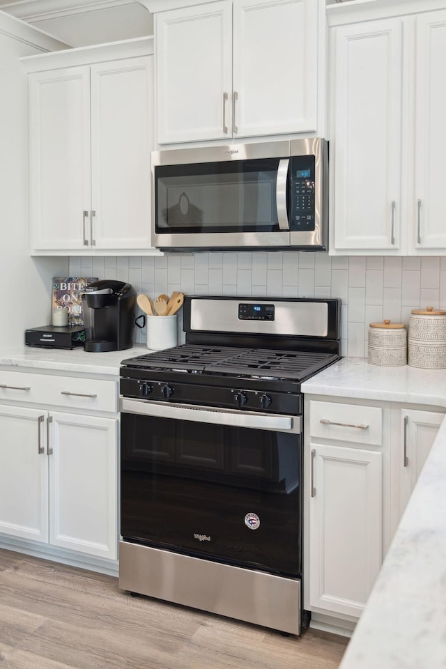 770 Opal Wing St, Moncks Corner, SC 29461 - kitchen with stainless steel appliances, white cabinets, tasteful backsplash, and light wood finished floors
