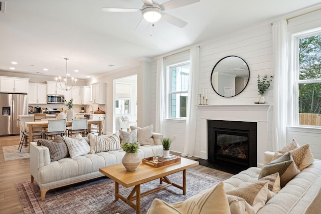770 Opal Wing St, Moncks Corner, SC 29461 - living area featuring light wood-style floors, a ceiling fan, a large fireplace, a chandelier, and crown molding