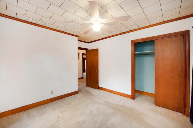 unfurnished bedroom with crown molding, light carpet, ceiling fan, and a closet