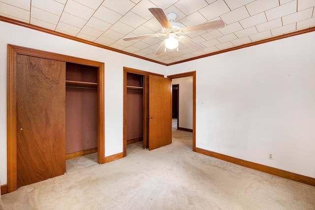 unfurnished bedroom featuring crown molding, light carpet, two closets, and ceiling fan