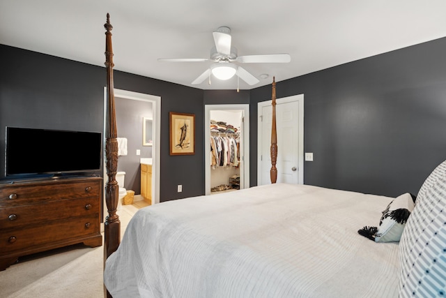 bedroom with a closet, ensuite bathroom, ceiling fan, a spacious closet, and light colored carpet