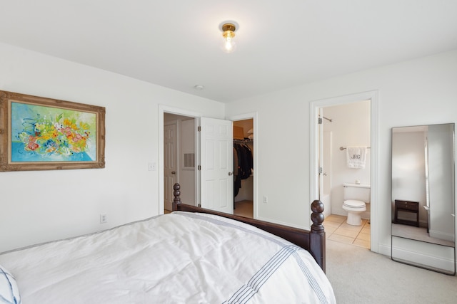 bedroom with baseboards, light tile patterned floors, connected bathroom, a walk in closet, and light carpet