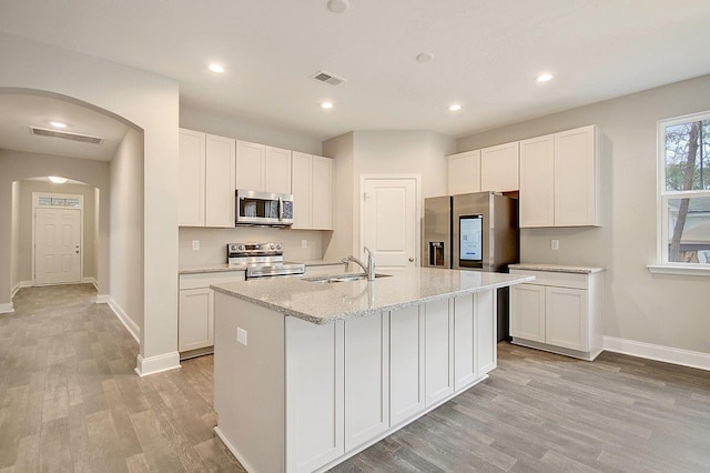 kitchen featuring visible vents, arched walkways, a sink, appliances with stainless steel finishes, and white cabinetry