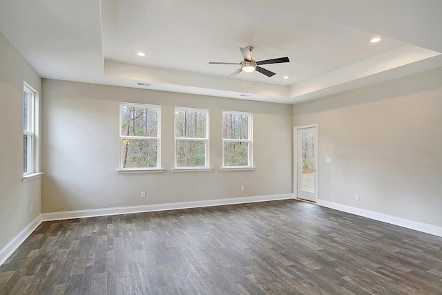 spare room featuring dark wood-style floors, recessed lighting, baseboards, and a tray ceiling