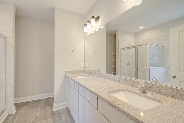 full bath featuring a stall shower, wood finished floors, baseboards, and a sink