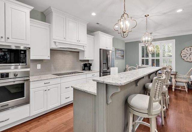 1033 Tuckers Rd, Pawleys Island, SC 29585 - kitchen featuring an inviting chandelier, stainless steel appliances, white cabinetry, backsplash, and under cabinet range hood