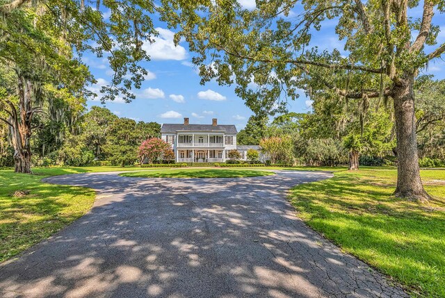 1033 Tuckers Rd, Pawleys Island, SC 29585 - view of front of home featuring covered porch, curved driveway, a chimney, and a front yard