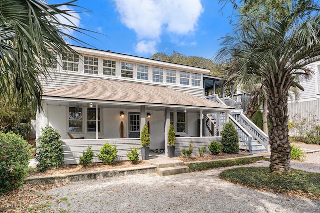 504 W Ashley Ave, Folly Beach, SC 29439 - view of front facade featuring roof with shingles, a porch, stucco siding, and stairway