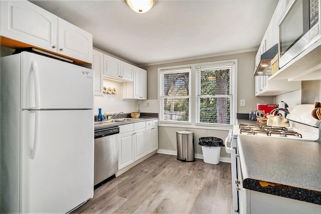 504 W Ashley Ave, Folly Beach, SC 29439 - kitchen featuring appliances with stainless steel finishes, white cabinets, light wood-style flooring, crown molding, and extractor fan