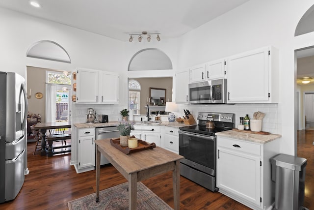 kitchen featuring dark wood-type flooring, sink, white cabinetry, stainless steel appliances, and light stone countertops