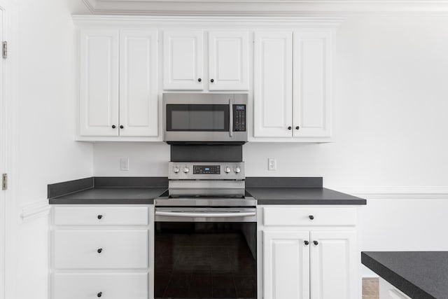 kitchen featuring stainless steel appliances, dark countertops, and white cabinets