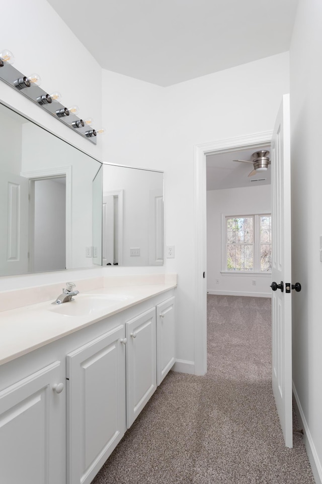 bathroom featuring carpet, baseboards, and vanity