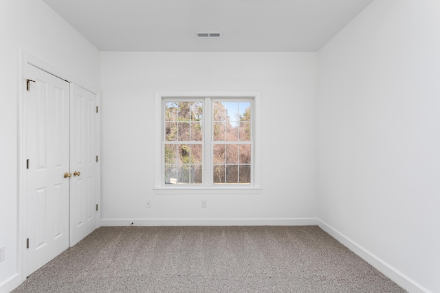 unfurnished bedroom with a closet, carpet, visible vents, and baseboards