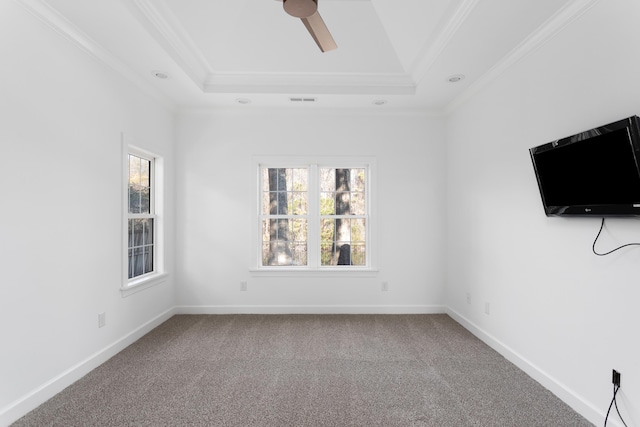 carpeted spare room with baseboards, a tray ceiling, ceiling fan, and crown molding