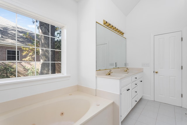 bathroom featuring lofted ceiling, vanity, a tub with jets, and tile patterned floors