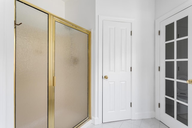 full bath with a shower stall and baseboards