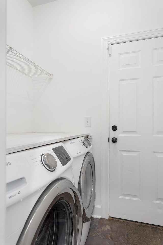 laundry area featuring laundry area, stone finish floor, and washing machine and clothes dryer